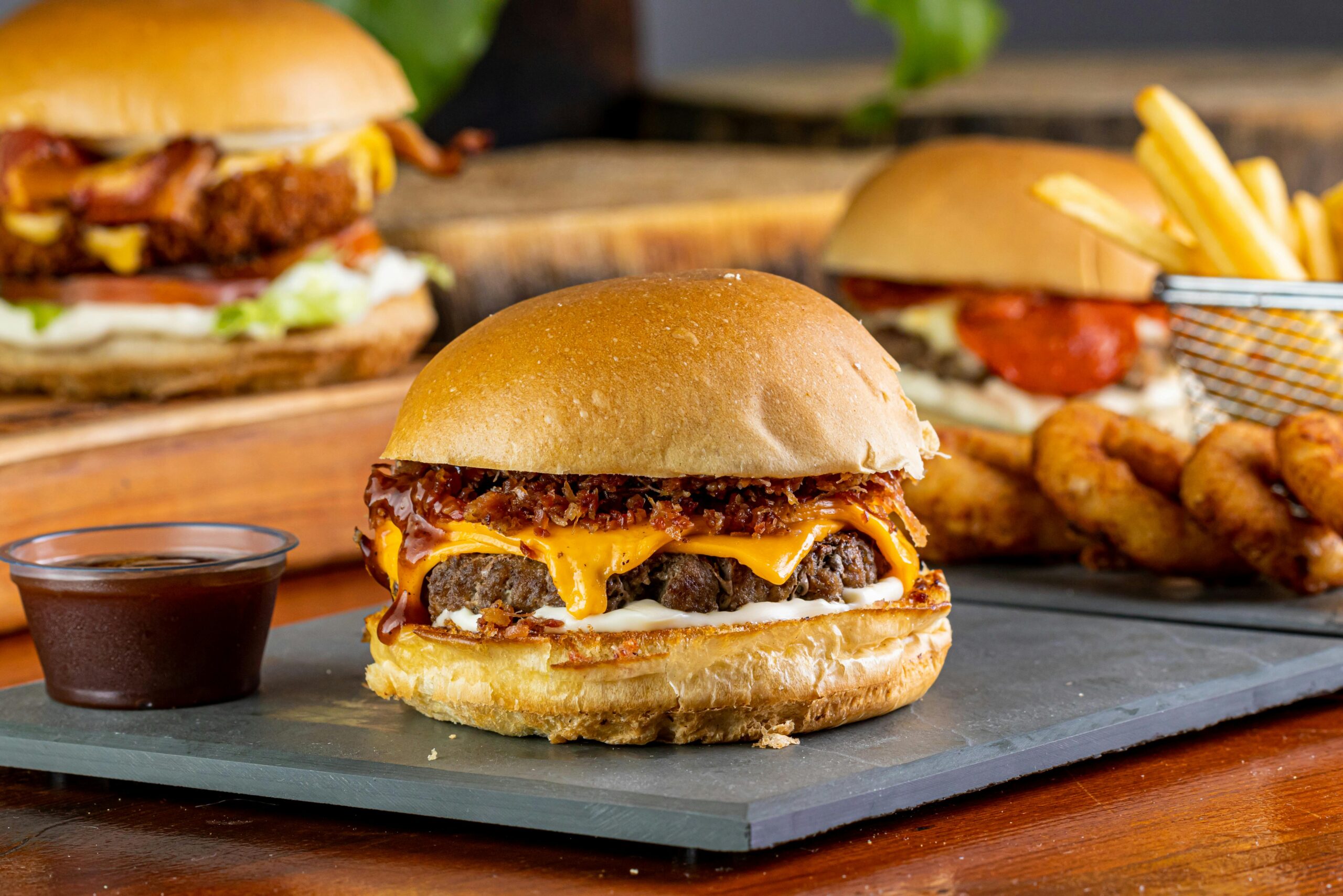 Mouthwatering gourmet burgers served with onion rings, fries, and a tangy dipping sauce.